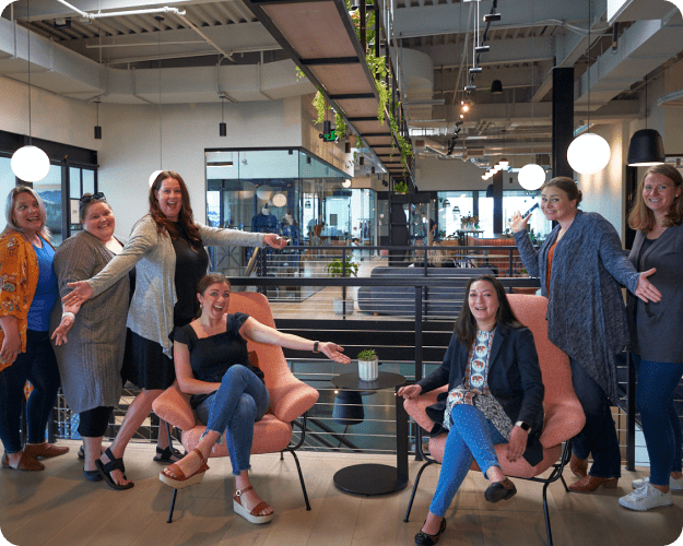 A group of female teammates have fun posing for a picture in an office environment.
